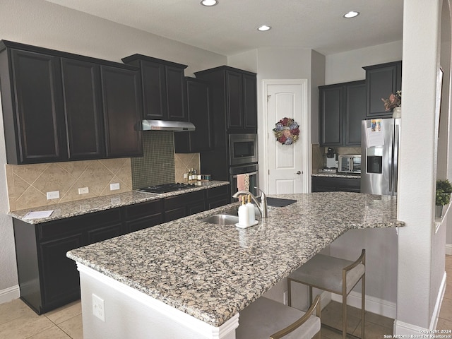 kitchen with light stone counters, appliances with stainless steel finishes, light tile floors, sink, and tasteful backsplash