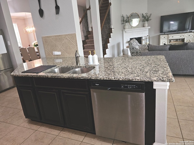 kitchen with appliances with stainless steel finishes, light tile flooring, light stone counters, a fireplace, and sink