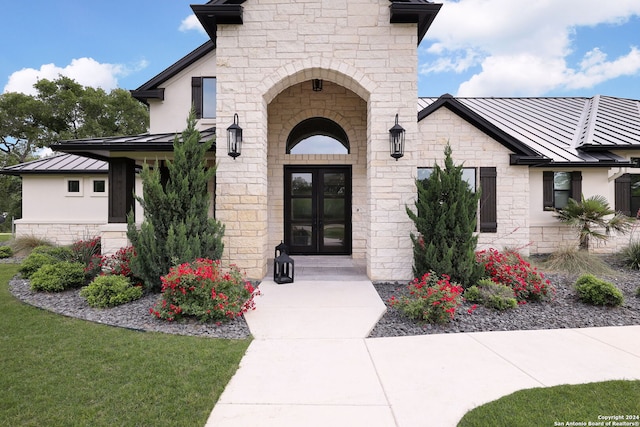 view of exterior entry featuring french doors and a lawn