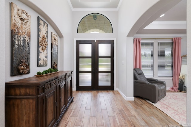 foyer featuring french doors, crown molding, and light wood-type flooring