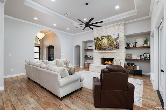 living room with light hardwood / wood-style flooring, crown molding, ceiling fan, and a fireplace