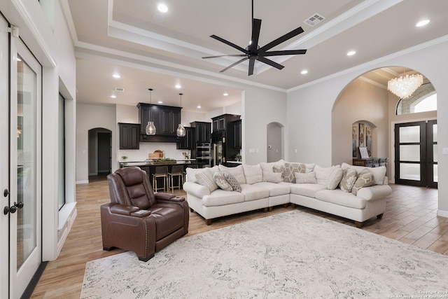 living room with ornamental molding, light hardwood / wood-style floors, ceiling fan, and a raised ceiling