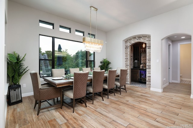 dining space with light hardwood / wood-style flooring, a chandelier, and beverage cooler