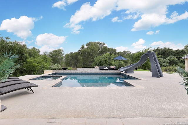 view of swimming pool with a patio area, a water slide, and an in ground hot tub