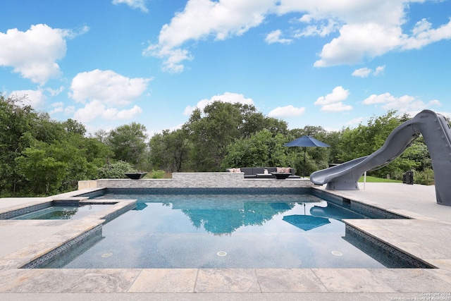 view of pool with a patio, a water slide, and an in ground hot tub