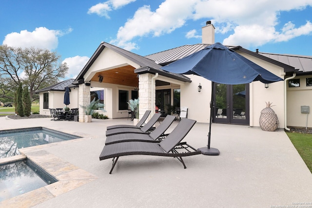 back of property with french doors, a patio, and a swimming pool with hot tub