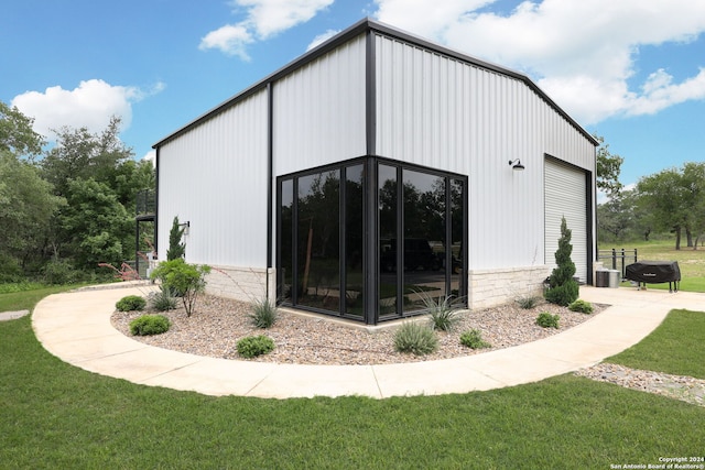 view of side of property with a garage, a lawn, and an outdoor structure