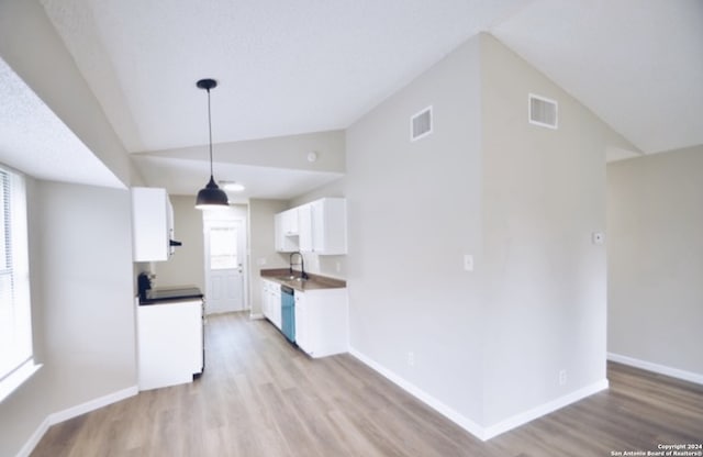 kitchen with plenty of natural light, vaulted ceiling, light wood-type flooring, and white cabinetry