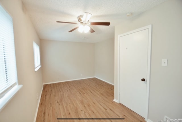 empty room with light hardwood / wood-style floors, ceiling fan, and a textured ceiling