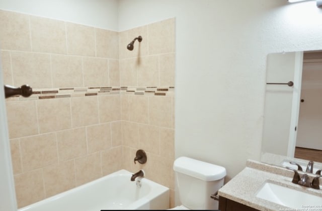 full bathroom featuring tiled shower / bath combo, toilet, and vanity