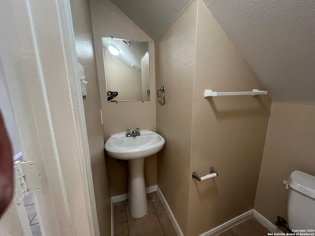 bathroom featuring lofted ceiling, tile floors, and toilet