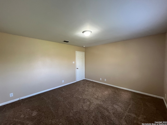 unfurnished room featuring dark colored carpet