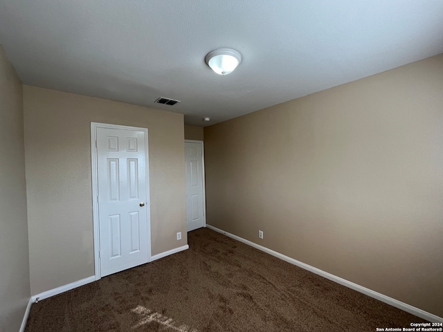 unfurnished room featuring dark colored carpet