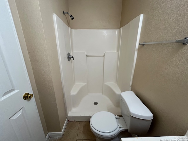 bathroom featuring walk in shower, toilet, and tile flooring