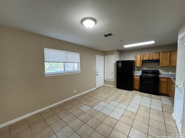 kitchen featuring black fridge, light tile floors, and stove