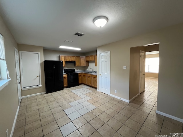 kitchen with sink, light tile flooring, and black appliances