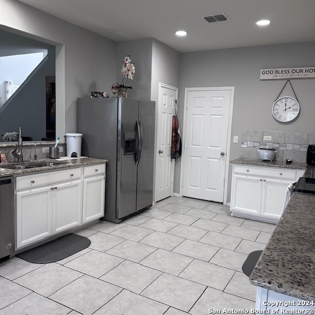 kitchen featuring dark stone counters, stainless steel appliances, white cabinets, and light tile floors