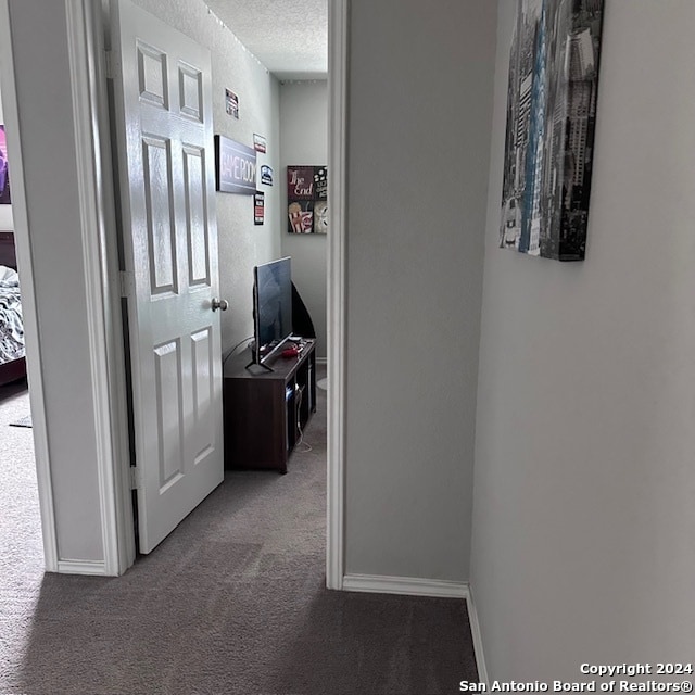 hallway with a textured ceiling and carpet floors