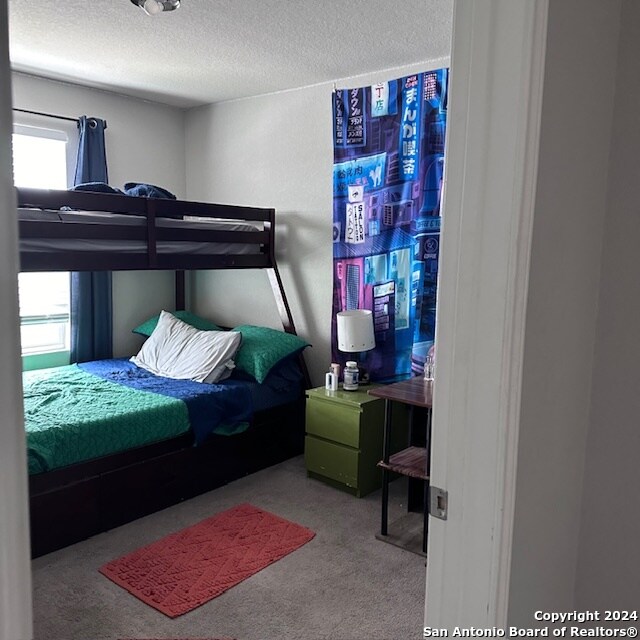 bedroom featuring a textured ceiling, carpet, and multiple windows