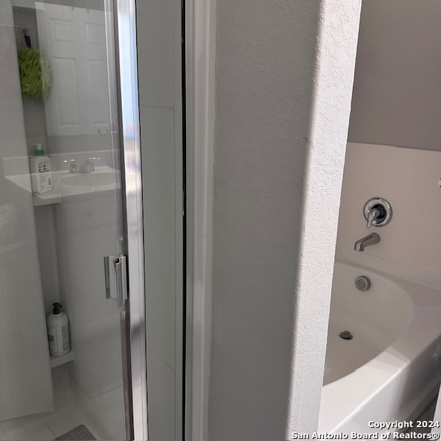 bathroom with a washtub, tile floors, and vanity