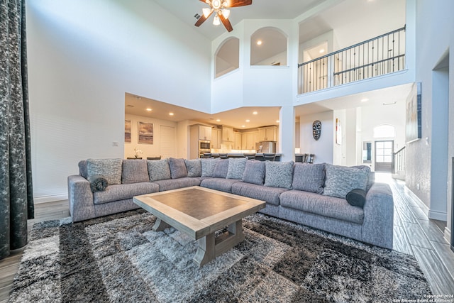 living room featuring ceiling fan and a towering ceiling