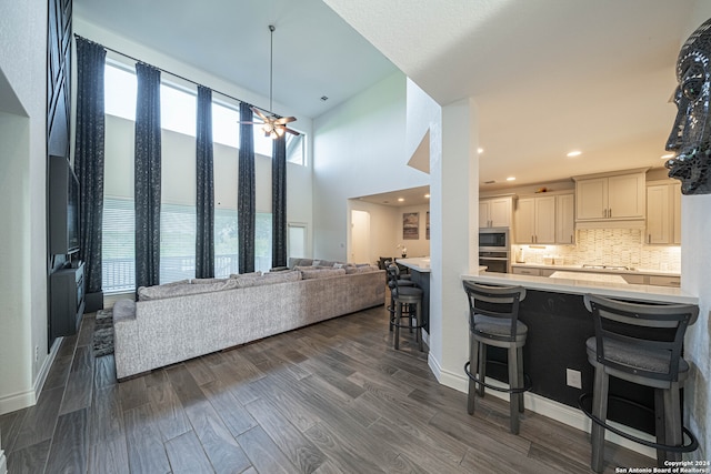 interior space featuring dark hardwood / wood-style flooring, backsplash, stainless steel appliances, a breakfast bar area, and ceiling fan