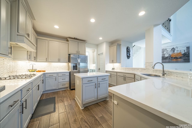 kitchen featuring backsplash, stainless steel appliances, dark wood-type flooring, sink, and a center island