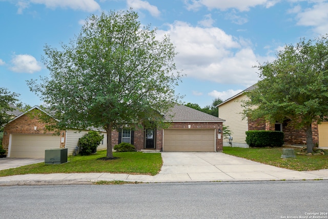 view of property hidden behind natural elements with a garage and a front lawn