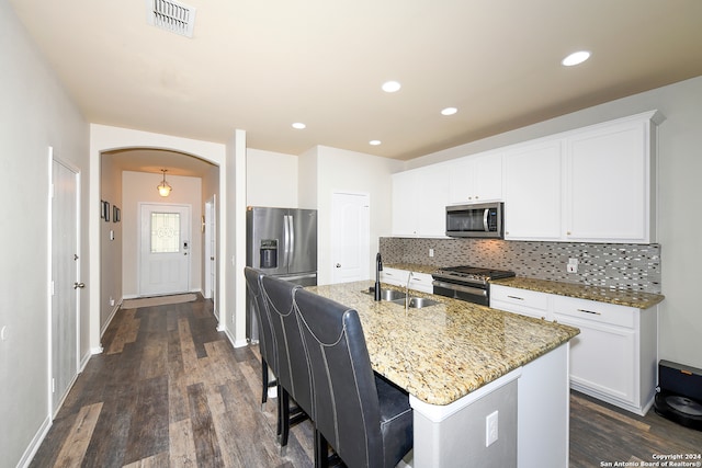 kitchen with appliances with stainless steel finishes, tasteful backsplash, an island with sink, white cabinetry, and sink