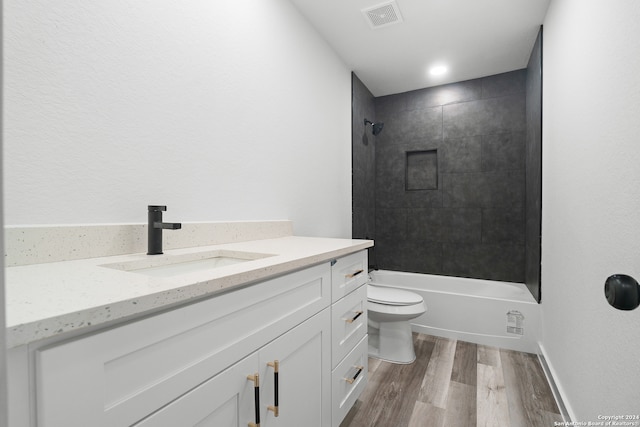 full bathroom featuring vanity, hardwood / wood-style flooring, toilet, and tiled shower / bath combo