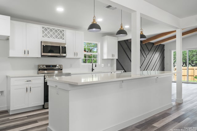 kitchen featuring appliances with stainless steel finishes, a center island, white cabinets, hanging light fixtures, and hardwood / wood-style flooring