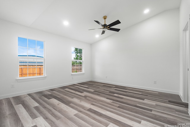 empty room with ceiling fan, hardwood / wood-style floors, and lofted ceiling