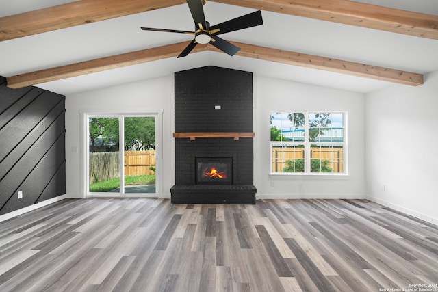 unfurnished living room with lofted ceiling with beams, wood-type flooring, brick wall, and a fireplace