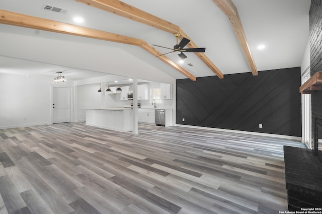 unfurnished living room with ceiling fan, a brick fireplace, vaulted ceiling with beams, and hardwood / wood-style floors