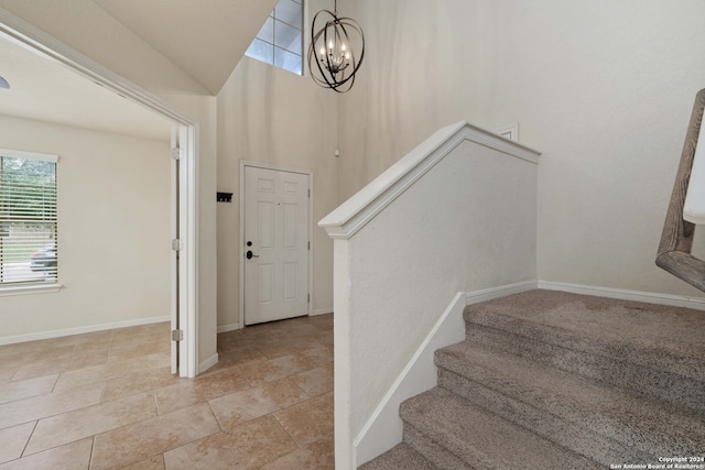 staircase with an inviting chandelier and light tile flooring