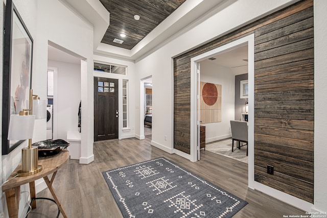 foyer entrance featuring wooden ceiling, a raised ceiling, and dark hardwood / wood-style flooring