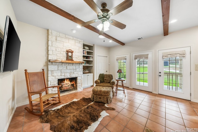 living room with beamed ceiling, a fireplace, light tile floors, and built in shelves