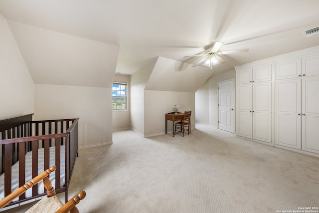 carpeted bedroom featuring lofted ceiling, ceiling fan, and a nursery area