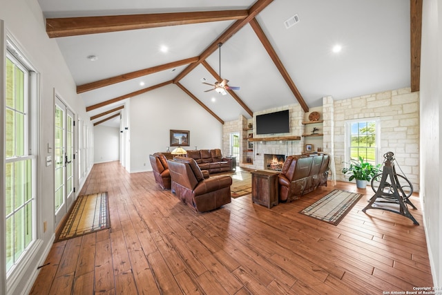 living room with plenty of natural light, high vaulted ceiling, a stone fireplace, ceiling fan, and hardwood / wood-style flooring