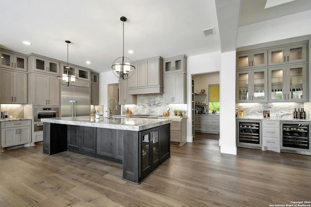 kitchen with decorative light fixtures, appliances with stainless steel finishes, beverage cooler, and gray cabinets