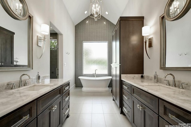 bathroom featuring vanity, vaulted ceiling, tile patterned floors, an inviting chandelier, and a bathtub