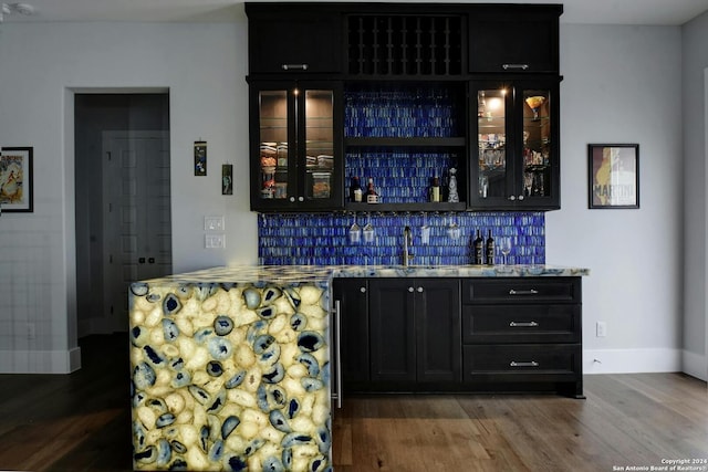 bar with wood-type flooring and backsplash