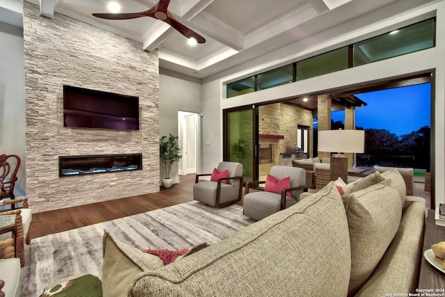 living room featuring hardwood / wood-style floors, beamed ceiling, a fireplace, ceiling fan, and coffered ceiling