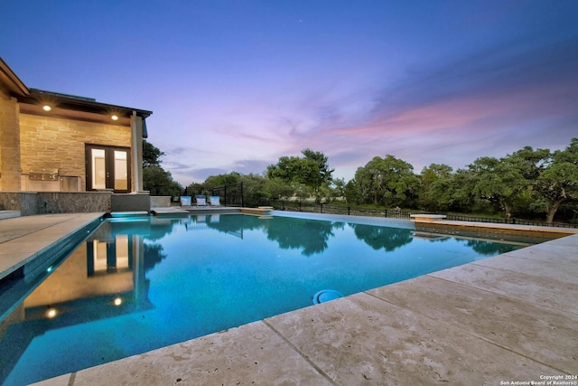 pool at dusk featuring french doors