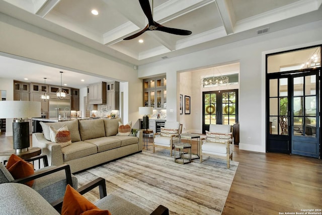 living room featuring ceiling fan, beamed ceiling, coffered ceiling, light hardwood / wood-style flooring, and ornamental molding