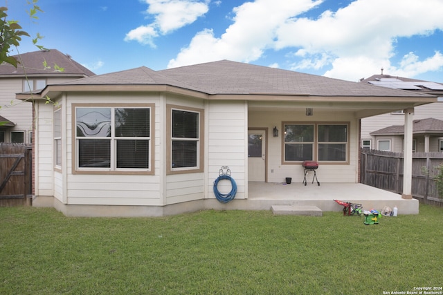 back of house featuring a patio, a lawn, and solar panels