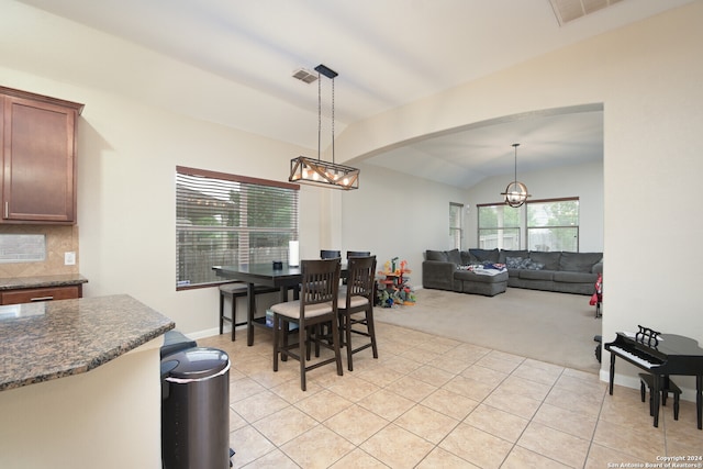 tiled dining room with an inviting chandelier and vaulted ceiling