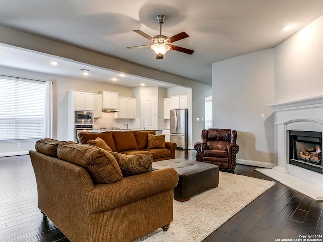 living room featuring wood-type flooring, sink, and ceiling fan