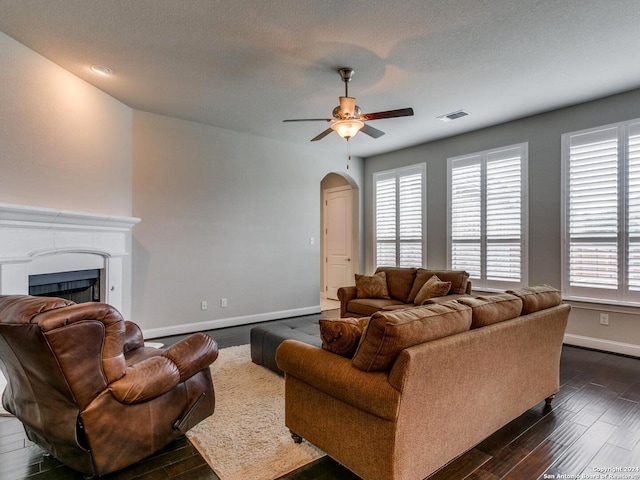 living room featuring dark hardwood / wood-style flooring, ceiling fan, and a textured ceiling