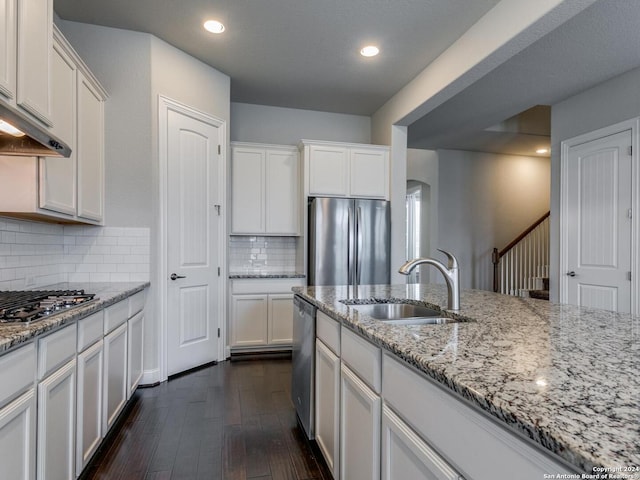 kitchen featuring appliances with stainless steel finishes, white cabinets, sink, backsplash, and dark wood-type flooring